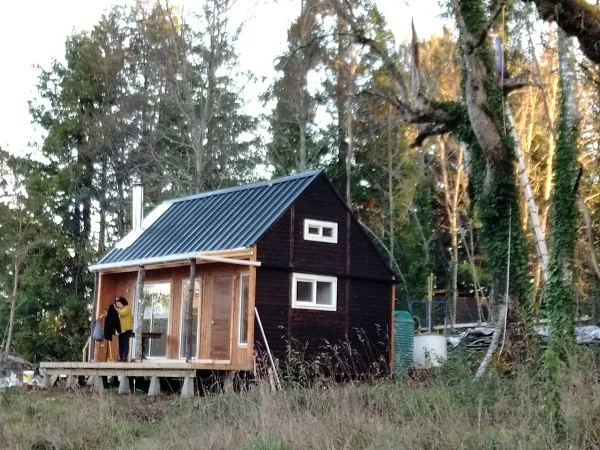 Foto real de la casa piloto de madera, con su estanque al costado